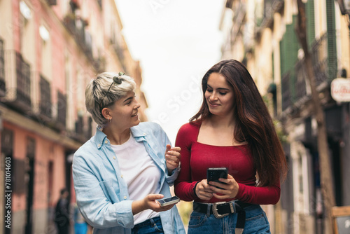 two teenager girls walking and using her mobiles photo