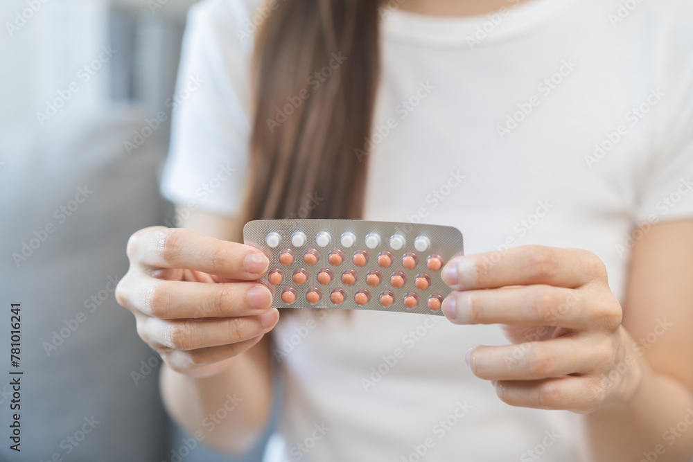 Contraception and pregnancy, menstruation concept, birth control pills asian young woman hand holding hormonal oral contraceptives medicine, take pharmaceutical to prevention, safe virus sex disease. - obrazy, fototapety, plakaty 