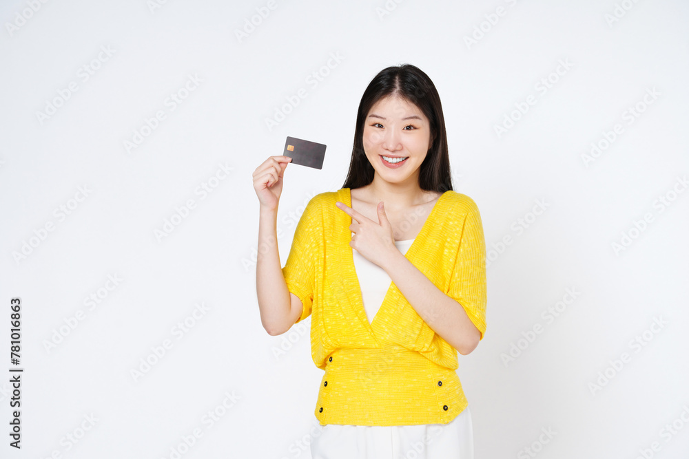 Naklejka premium Happy young Asian woman smiling, showing and pointing credit card for paying online business isolated on white background