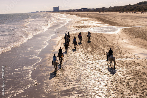 group of people horseback riding on the beach along the ocean © Bill Keefrey