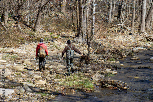 two men walking in woods along stream with fishing gear © Bill Keefrey