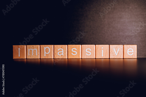 Wooden blocks form the text "Impassive" against a black background.