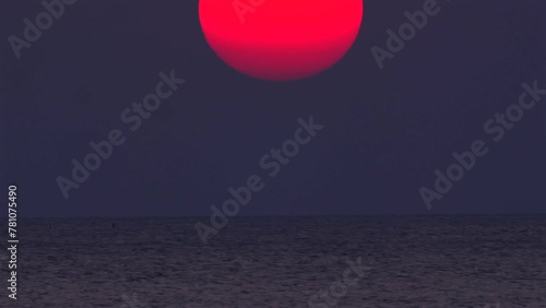 Serene sunset view over ocean with large red sun sinking into horizon, tranquil scene for meditation and reflection. Peaceful nature background. Timelapse photo