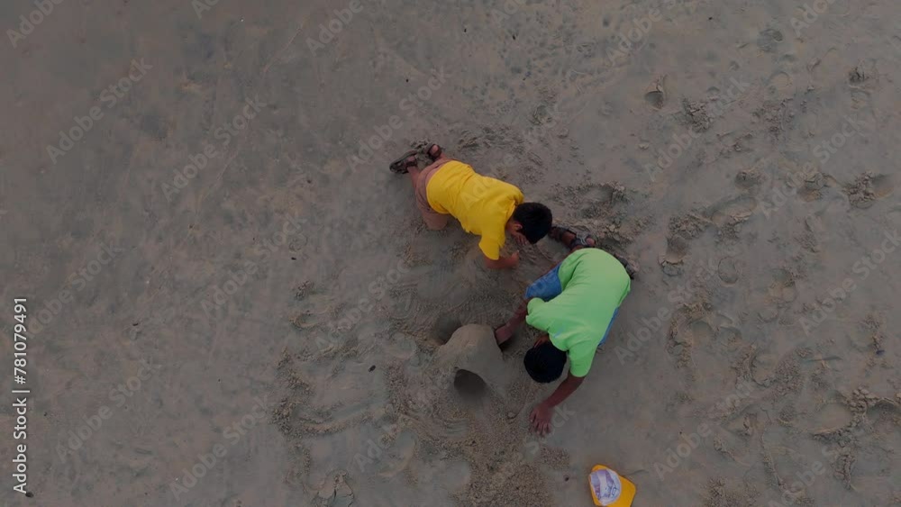 Brothers playing in beach, children's playing with sand at sunset Brothers playing in beach, children's playing with sand at sunset