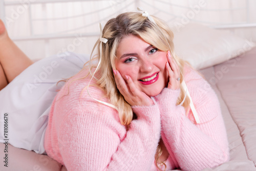 Happy curvy woman in sweater lying on bed