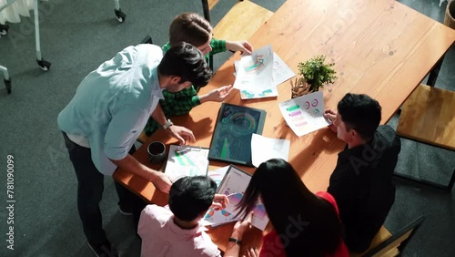 Top view of diverse group brainstorming marketing idea while looking at financial graph or stock market statistic chart report. Skilled business team share plan about start up project. Convocation. photo
