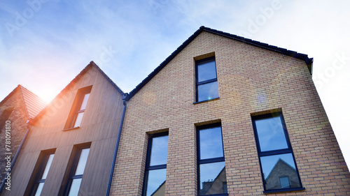 New single family houses in a new development area. Residential homes with modern facade. Terraced family homes in newly developed housing estate. The real estate market in the suburbs.