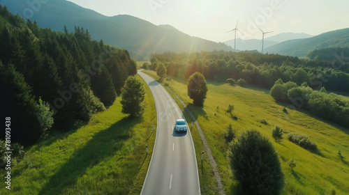 Electric car on the road in the countryside, driving on sunny day near forest and green hills. Modern white automobile, traveling by car. Eco-friendly technology, sustainable life concept