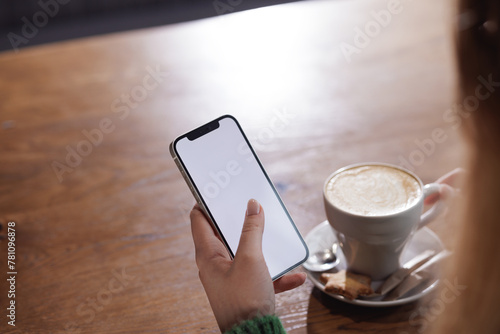 Payment by NFC phone. A woman pays contactlessly using a phone with NFC technology. Wireless money transactions. Card machine in a woman's hand on the background of a cafe