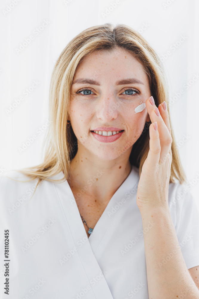 The face of a beautiful woman applying cosmetic cream to her skin. Facial. Facial skin care procedure. Moisturizing the face The face of a beautiful woman applying cosmetic cream to her skin. Facial. Facial skin care procedure. Moisturizing the face