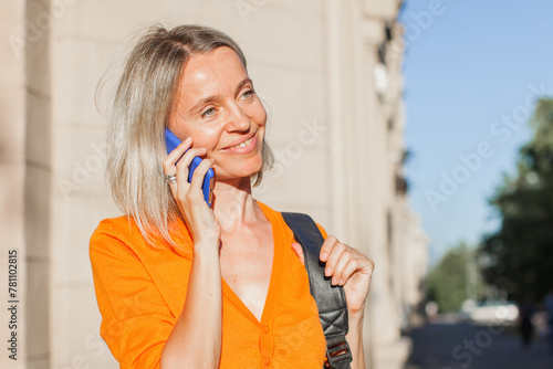 Happy middle aged woman outside in city with mobile phone