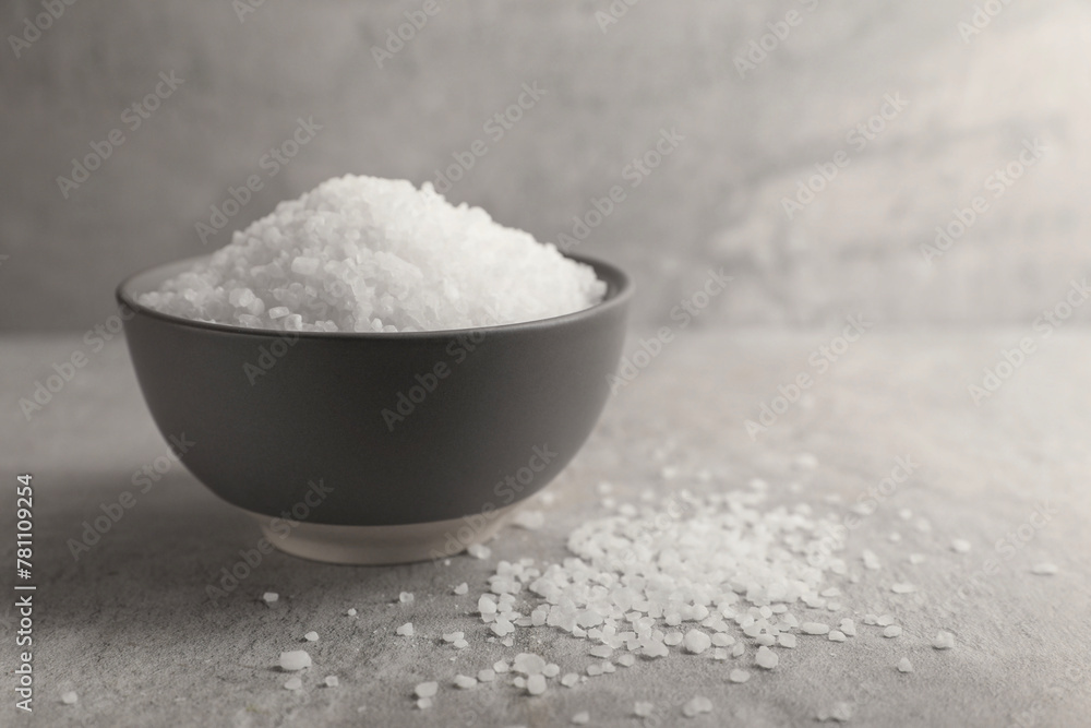 Natural salt in bowl on grey textured table, space for text Natural salt in bowl on grey textured table, space for text