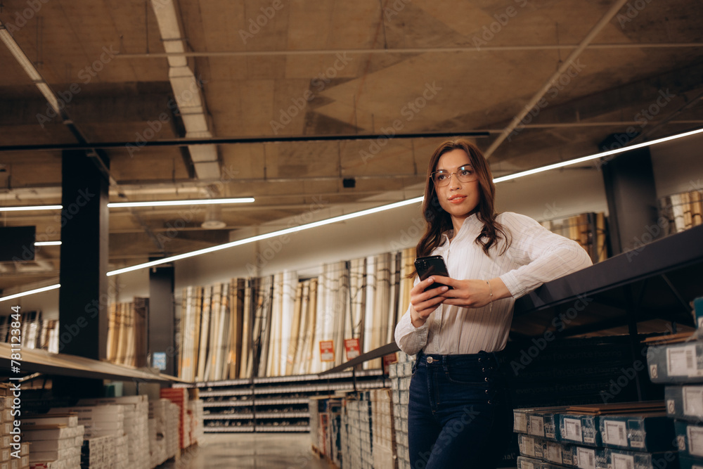 Fototapeta premium Woman with phone configuring at the hardware store