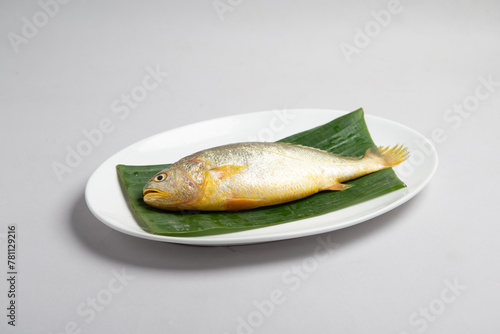 bbq baked grilled giant whole kampong fish with organic Himalayan salt and lime seasoning in banan leaf plate on white background appetiser halal food hotel cuisine restaurant menu