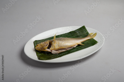 bbq baked grilled giant whole kampong fish with organic Himalayan salt and lime seasoning in banan leaf plate on white background appetiser halal food hotel cuisine restaurant menu