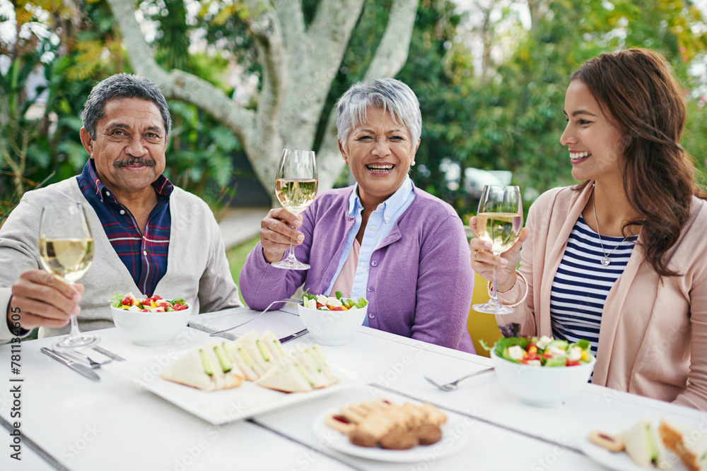 Happy family and sitting with food or lunch together outside for celebration on summer vacation or holiday. Parents and woman, wine, toast and cheers with smile for weekend meal or tradition on break