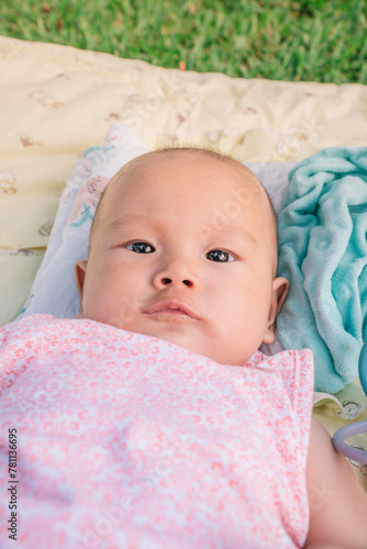 Infant Baby Girl is laying on her back in a pink bodysuit.