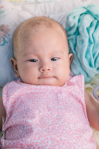 Infant Baby Girl is laying on her back in a pink bodysuit.