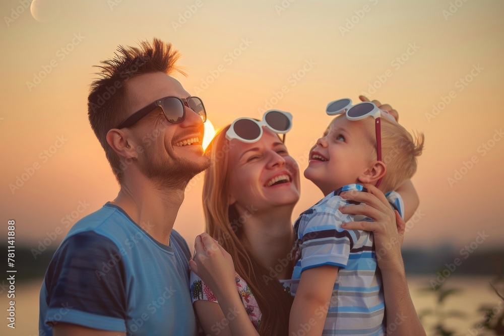 Young Family Enjoying Sunset at the Lake - Smiling Parents and Child in Casual Wear Young Family Enjoying Sunset at the Lake - Smiling Parents and Child in Casual Wear