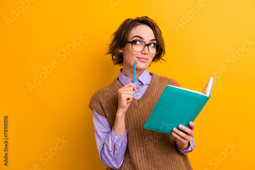 Photo of smart girl dressed knitwear waistcoat hold copybook look at promo empty space write plan isolated on yellow color background © deagreez