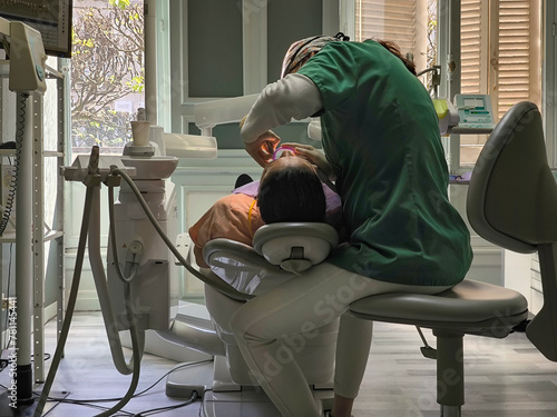 Dentista atenciosa a tratar dente de paciente em consultório odontológico