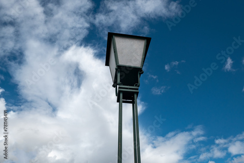 Poste antigo de iluminação pública com um bonito céu azul e algumas nuvens de fundo
 photo