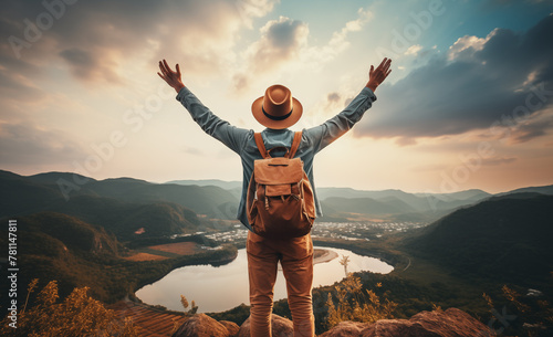 Ecstatic explorer with backpack observed from behind at the mountain summit
