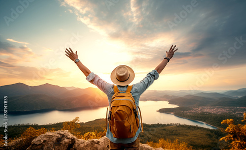 Joyful hiker with backpack seen from behind atop the mountain