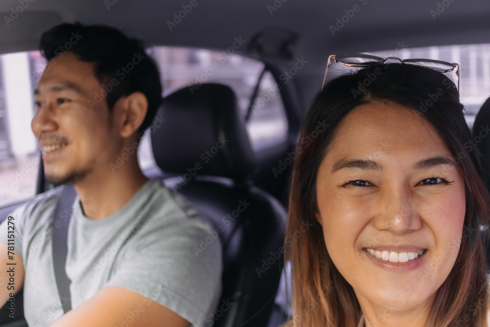 Asian Thai couple traveling by a car, woman taking selfie while man is driving on road. Asian Thai couple traveling by a car, woman taking selfie while man is driving on road.