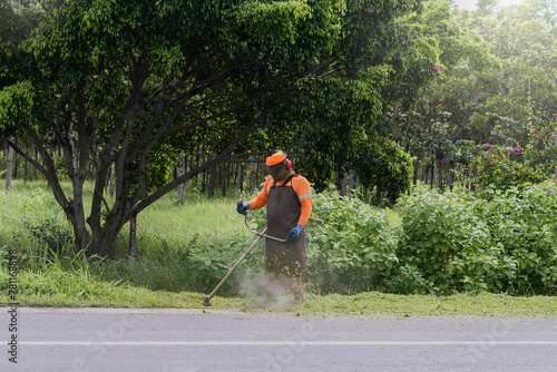 Groundskeeper Using a String Trimmer Beside a Road photo