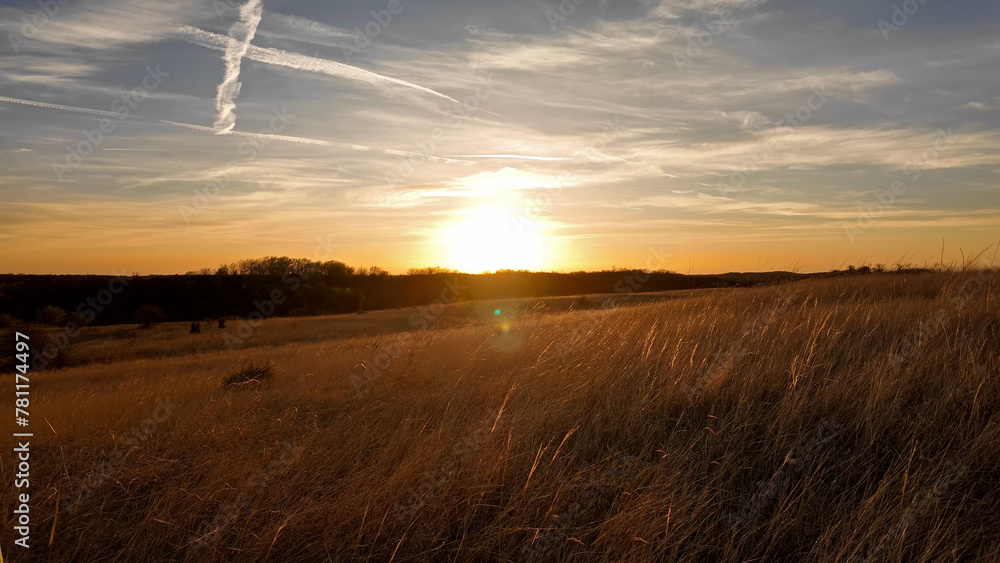 Fototapeta premium Sunset with some clouds and golden colored landscape.