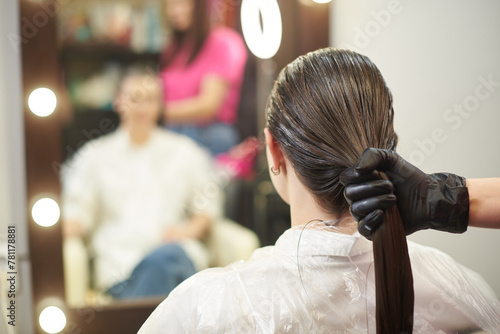 The hair stylist holds the hair tail soaked in keratin