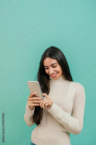 Portrait of a beautiful girl looking at the phone on a mint background 