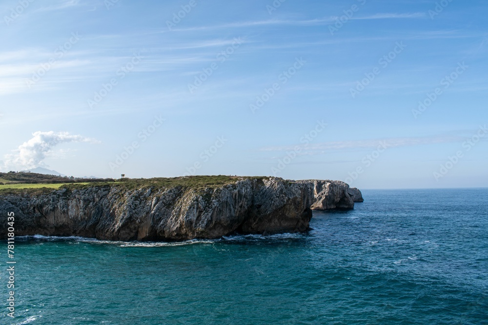 Scenic view of a rocky coastline against a blue sea on a sunny day