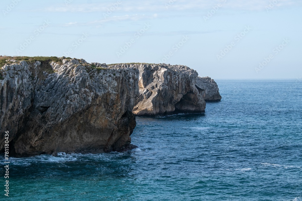 Scenic view of a rocky coastline against a blue sea on a sunny day