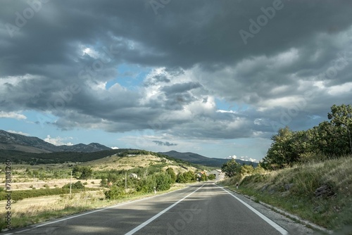 View of the open countryside road with a bright blue sky and mountains in the background