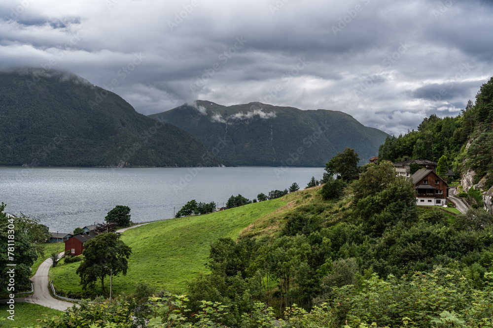 Stormy Skies Over Tingvollfjorden Near Ålvundeid Village. Overcast weather looms above the tranquil fjord with rural Norwegian houses nestled in lush greenery. In Møre og Romsdal county Norway