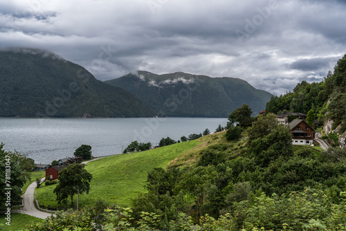 Stormy Skies Over Tingvollfjorden Near Ålvundeid Village. Overcast weather looms above the tranquil fjord with rural Norwegian houses nestled in lush greenery. In Møre og Romsdal county Norway photo