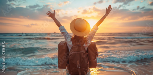 A happy woman traveler with arms raised in joy Back view of happy excited raising arms up to blue sky - Hipster enjoying summer sunset at the beach - Travel, mental health, success, business, tourism photo