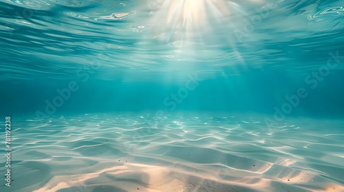 Blue tropical ocean above, seabed sand below, empty underwater background with the summer sun shining brightly, creating ripples in the calm sea water. © horizon