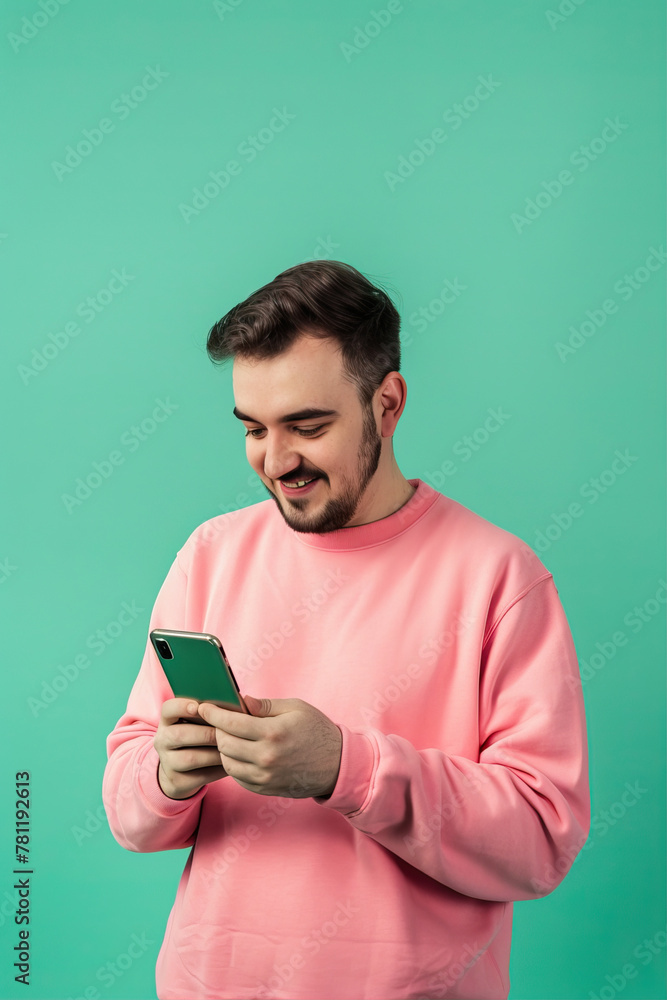A man on a turquoise background looks at the phone
A man on a turquoise background looks at the phone