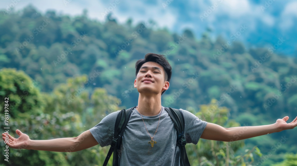 Portrait of a free happy Asian man with open arms enjoying life in meadows and nature background , young joyful chinese male with good mental health Portrait of a free happy Asian man with open arms enjoying life in meadows and nature background , young joyful chinese male with good mental health