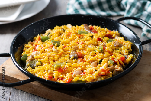 Yellow rice with chicken and vegetables on wooden table
