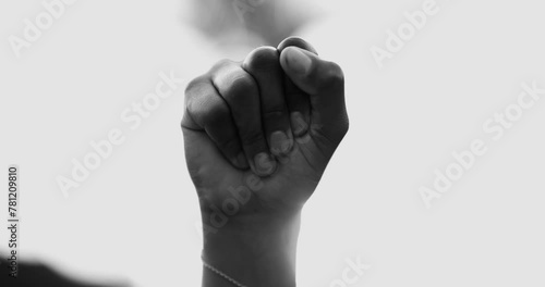 Close-up fist in the air symbolizing empowerement. African American woman raises hand in the air claiming independence and solidarity in black and white photo