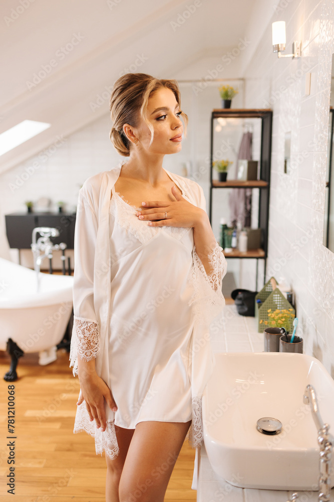 Beautiful and tender bride in white silk robe standing in luxury bathroom. Female preparing for wedding Beautiful and tender bride in white silk robe standing in luxury bathroom. Female preparing for wedding