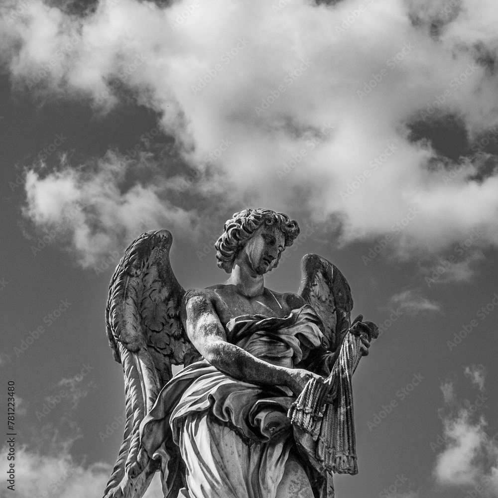 Grayscale of an angel statue against the daytime sky and clouds Grayscale of an angel statue against the daytime sky and clouds