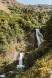 Vertical shot of a waterfall flowing down the rock covered in trees.
