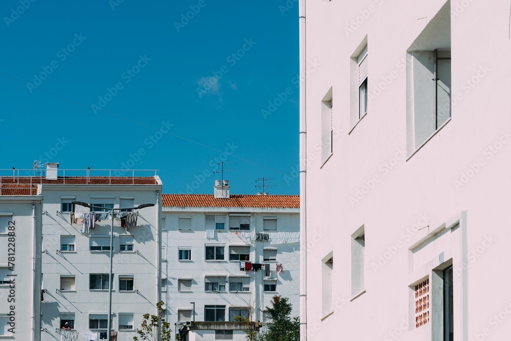 White residential building with hanging laundry and a blue sky in the background