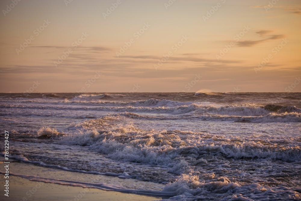Fototapeta premium Beautiful view of a sea with small waves during orange sunset