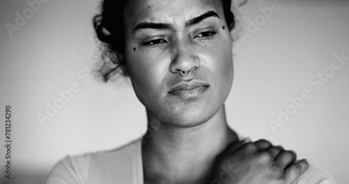 One preoccupied young black woman portrait feeling anxiety and worry during difficult times in dramatic black and white. Millennial person of African descent with pensive thoughtful emotion photo